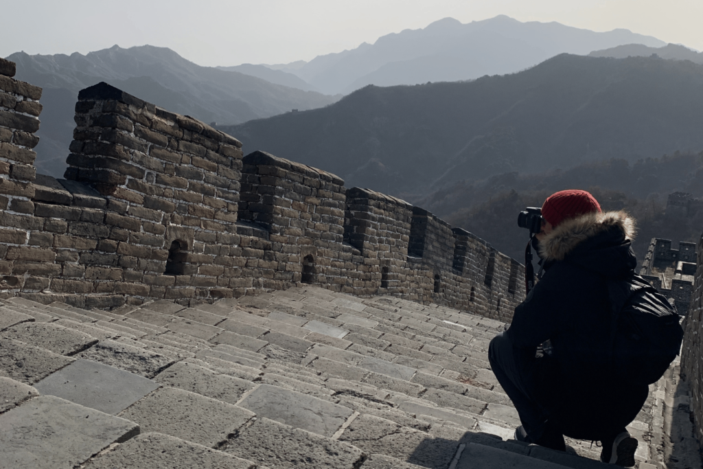 Jim Litherland on the Great Wall of China, kneeled and taking a photograph.